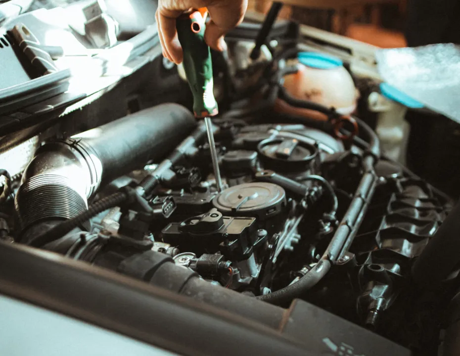 Informe de un coche de segunda mano: mano con un destornillador revisando el motor durante la inspección